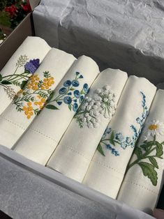 a box filled with white napkins covered in embroidered flowers