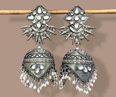 Add elegance and sophistication to any casual day with these silver-toned handcrafted Metal Jhumkas. It's a beautiful pair of oxidized silver metal alloy Jhumkas embellished with Ghungroos & Mirrors.  Features: -Base Metal- Copper -Plating- German Silver -Stone- Mirror -Sizing- Non Adjustable -Type- Jhumkas earrings -Antique traditional look  -Black polish long earrings -Bollywood Style -Afghani Look -FREE Shipping -Gift Wrapping Available -Delivery from a Small Business in India -Handmade Produ Silver Chandelier Earrings With Tilla For Gifts, Silver Danglers For Navratri Party, Silver Bollywood Jhumkas With Matching Earrings, Silver Danglers For Party And Navratri, Silver Danglers For Party During Navratri, Elegant Silver Danglers For Navratri, Silver Fusion Style Drop Jhumkas, Silver Metal Bollywood Danglers, Silver Bollywood Style Drop Jhumkas