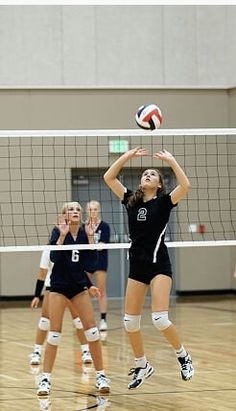 two girls playing volleyball on a court with people watching from the sidelines behind them