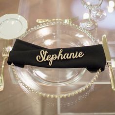 there is a place setting with silverware and black napkins on the glass plate