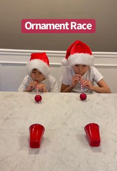 two children wearing santa hats sitting at a table