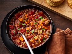 a bowl of soup on a table with muffins next to it and a wooden cutting board