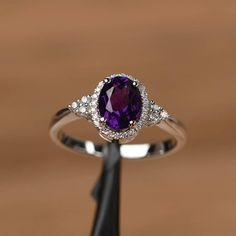 an oval shaped amethorate and diamond ring on top of a wooden table