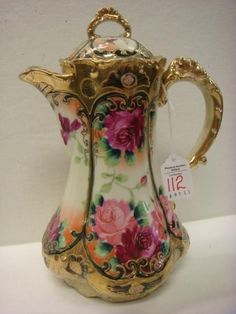 an ornately decorated vase with gold trimming and pink flowers on it's sides