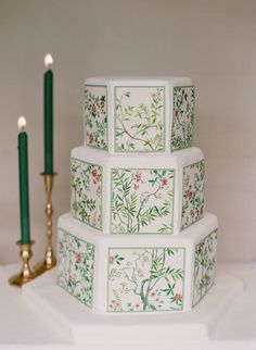 a three tiered cake sitting on top of a table next to two lit candles