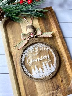 a christmas ornament on a cutting board with pine cones and evergreen branches in the background