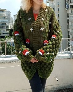 a woman wearing a green knitted sweater with red and white christmas decorations on it