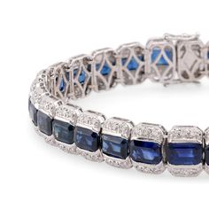 Center Stone: 29 Emerald Cut Blue SapphireWeight: 22 CaratsAccent Stone: 174 Round Brilliant Cut DiamondsWeight: 2 CaratsColor: GClarity: VSMetal: 18K White GoldEra: VintageCirca: 1990sSize: 7 1/8 inches in lengthGram weight: 24.56This stunning vintage bracelet from the 1990s is crafted in luxurious 18K white gold and features 29 vibrant emerald cut blue sapphires, totaling 22 carats. The sapphires are beautifully complemented by 174 sparkling round brilliant cut diamonds, totaling 2 carats, wit White Gold Sapphire Tennis Bracelet For Formal Occasions, Luxury Sapphire Tennis Bracelet For Formal Occasions, Classic Sapphire Bracelets For Formal Occasions, Luxury Sapphire Bracelet For Formal Occasions, Formal White Gold Sapphire Tennis Bracelet, Formal Sapphire Tennis Bracelet In Fine Jewelry Style, Luxury Sapphire Diamond Bracelet For Formal Occasions, Luxury Sapphire Diamond Bracelet For Formal Events, Brilliant Cut Sapphire Bracelet For Wedding