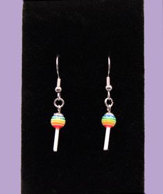 Add a pop of color and fun to your accessory collection with these delightful Lollipop Earrings, a charming addition to your jewelry collection. These unique earrings feature adorable lollipop designs in vibrant colors, symbolizing playfulness and joy. Perfect for any occasion, these earrings add a touch of whimsy and fun to your look. Product Details: Material: High-Quality Stainless Steel Hooks and colorful, high-quality materials for the lollipop shapes. Weight: Lightweight design at just 0.10oz, ensuring all-day comfort. Length: 1 inch, offering a playful yet striking presence. Design: Intricately detailed with lollipop designs in various colors (rainbow, blue, purple, red and green), showcasing fine craftsmanship. Features: Lightweight & Comfortable: Designed for extended wear without Playful Hypoallergenic Rainbow Earrings, Playful Rainbow Earrings With Ear Wire, Playful Rainbow Earrings, Lollipop Earrings, Charm Gift, Unique Earrings, Lollipop, Blue Purple, Jewelry Earrings Dangle