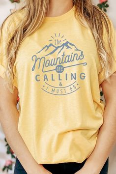 Introducing our "The Mountains Calling And I Must Go" Graphic Tee, a perfect choice for adventure enthusiasts and outdoor lovers. Most t shirt colors are 52/48 cotton/poly blend. White and Cream tees are 100% cotton, Ash tees are 99/1 cotton/poly. Available in various sizes, it's an excellent addition to outdoor retail stores and adventure-themed boutiques. Encourage your customers to answer the call of the mountains with our "The Mountains Calling And I Must Go" Graphic Tee. By Kissed Apparel.M Blue T-shirt With Letter Print For Outdoor, Blue Graphic Tee For Outdoor Activities, Blue Outdoor Tops With Screen Print, Blue Tops With Screen Print For Outdoor Activities, Blue Screen Print Tops For Outdoor Activities, Blue Screen Printed Tops For Outdoor Activities, Outdoor Blue T-shirt With Letter Print, Casual Tri-blend T-shirt For Adventure, Crew Neck Letter Print Hiking Top