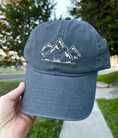 Hand embroidered hat with a light grey mountain landscape. Adjustable strap to fit all sizes with ponytail opening in back. 6.5in. hat depth Hand wash to preserve quality. Hand Embroidered Hats, Embroidered Mountains, Embroidered Hats Ideas, Beanie Embroidery, Outdoor Hut, Embroider Ideas, Mountain Hat, Outdoor Hat, Embroidery Caps