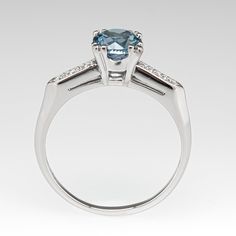 This stunning light icy teal sapphire engagement ring is centered with a round brilliant cut no heat Montana sapphire that we sourced and set in a vintage platinum diamond mounting. The shoulders are each bead set with three (3) round brilliant cut diamonds. The ring measures 7.3mm at the top, rises 7.3mm above the finger, tapering to 1.5mm wide and 1.2mm thick at the base of the shank. The ring is currently a size 9 and we offer complimentary sizing to fit. Aquamarine Brilliant Cut Diamond Ring For Formal Occasions, Formal Aquamarine Diamond Ring With Brilliant Cut, Classic Diamond Topaz Promise Ring, Classic Topaz Promise Ring With Diamond Accents, White Gold Brilliant Cut Aquamarine Rings, Anniversary Sapphire Ring With Side Stones In Round Cut, Classic Topaz Ring With Diamond For Promise, Anniversary Sapphire Ring With Round Cut Side Stones, Anniversary Sapphire Ring With Diamond Side Stones