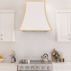 a stove top oven sitting inside of a kitchen next to white cabinets and cupboards