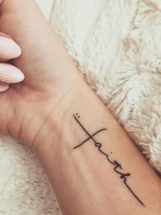 a woman's wrist with a cross and heartbeat tattoo on the left side of her arm