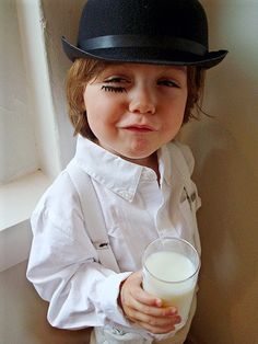 a little boy wearing a top hat and holding a glass of milk in his hand