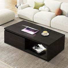 a coffee table with a laptop on it in the middle of a living room area