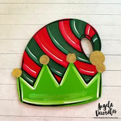 a green and red christmas ornament sitting on top of a wooden table next to a white wall