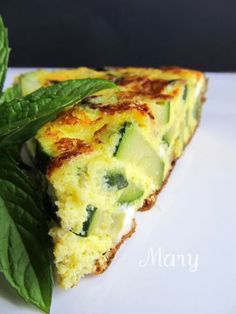 a slice of quiche on a white plate with green leaves