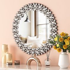 a mirror sitting on top of a table next to a vase filled with yellow flowers