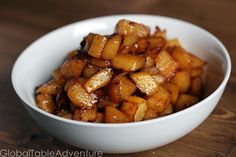 a white bowl filled with fried food on top of a wooden table