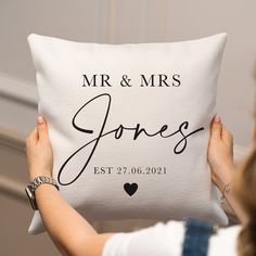 a woman holding up a pillow with the words mr and mrs on it in black ink