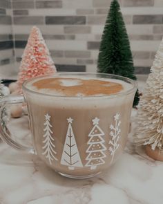 a cup of coffee sitting on top of a counter next to christmas trees and other decorations