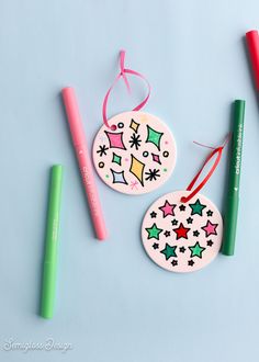 two christmas ornaments with markers and pens on a blue background