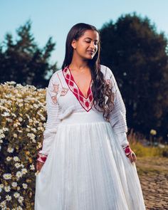 a woman wearing a white dress standing in front of flowers