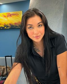 a woman with long black hair and tattoos on her arm