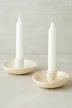 two white candles sitting on top of plates