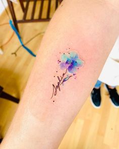 a watercolor style flower tattoo on the arm