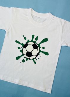 a white shirt with green paint splatters on it and a soccer ball in the center