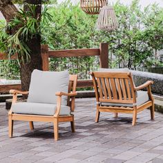 two wooden chairs sitting next to each other on a brick patio with trees in the background