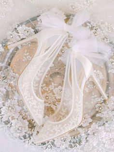 a pair of white high heel shoes on top of a lace doily covered plate