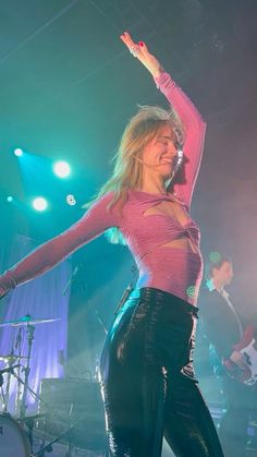 a woman standing on top of a stage with her arms in the air