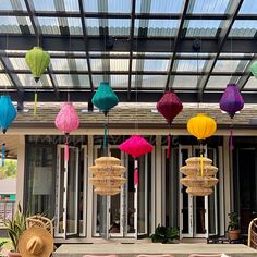 colorful lanterns hanging from the ceiling in front of a house