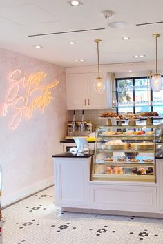 the inside of a bakery with lots of food on display and lights hanging above it