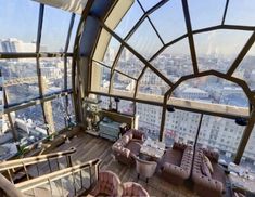 a room with couches, tables and windows overlooking the city