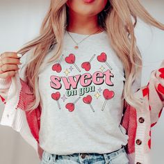 This Sweet on You lollipop candy heart t-shirt is a gift for yourself (or a sweetheart) on Valentine's Day or any time of year. Unisex sizing. Order up for an oversized look. DESCRIPTION * Our shirts are soft and comfortable and the styling possibilities are endless. Roll up the sleeves, tie a side knot, front tuck, or wear it while lounging around the house. * 100% Airlume combed and ringspun cotton (fiber content may vary for different colors). * Ribbed knit collars to bolster shaping.  * The shoulders have taping for better fit over time. Dual side seams hold the garment's shape for longer.  * Fitting is unisex, runs true to size. CARE INSTRUCTIONS * Cotton shirts will shrink about half a size (give or take). Recommended to wash inside out with cold water. Air or tumble dry. Do not blea Sweet Heart Candy, Heart Sucker, Valentines Graphic Tee, Valentine Graphic, Teacher Aesthetic, Lollipop Candy, Front Tuck, Heart T Shirt, Heart Shirt