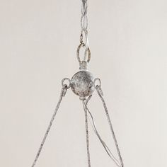 a metal object hanging from a chain on a white wall in the middle of an empty room