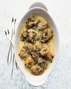 a white bowl filled with meat covered in gravy and garnished with silverware