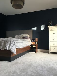 a bedroom with blue walls and carpeted flooring has a bed in the middle