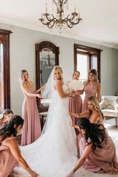 bridesmaids helping the bride put on her wedding dress