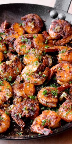 a skillet filled with cooked shrimp and garnished with parsley