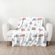 a couch covered in a blanket with cars on it