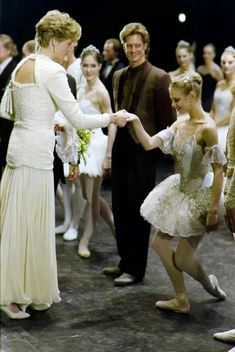 two ballerinas shaking hands in front of a crowd