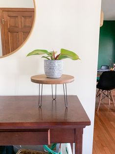 a potted plant sitting on top of a wooden table next to a round mirror