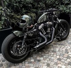 a black motorcycle parked on top of a cobblestone street