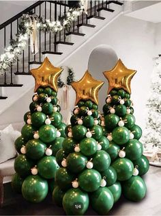 a christmas tree made out of balloons with gold stars on top and green balls in the middle