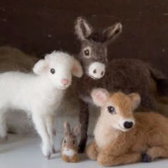 three stuffed animals sitting next to each other on top of a white surface with one animal looking at the camera